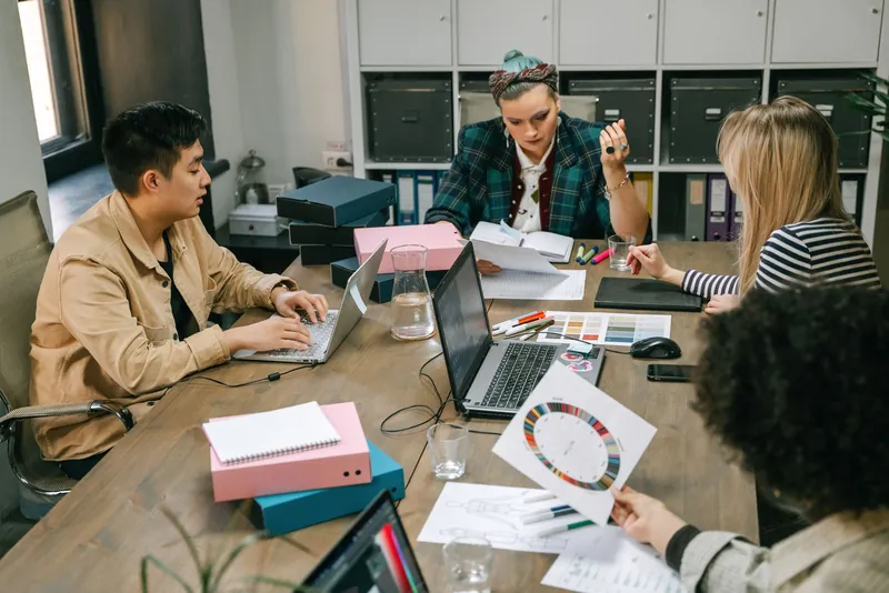 Des collègues échangent autour de leurs dossiers dans un bureau