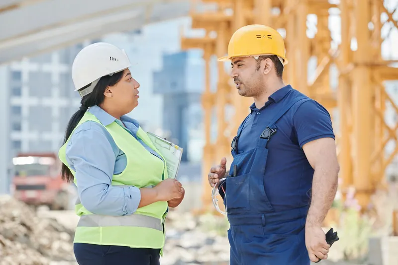 Deux professionnels en casque échangent sur un chantier
